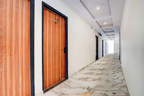 A corridor with wooden doors and a marble floor. - Collection O Radha Krishna Vrindavan (Vrindavan)