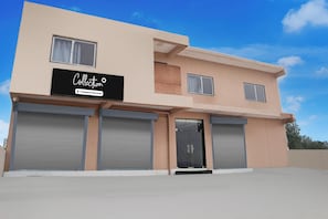 A two-story building with a sign that reads 'Collection Company-Serviced'. There are three large garage doors and two windows on the upper floor. - Collection O Radha Krishna Vrindavan (Vrindavan)