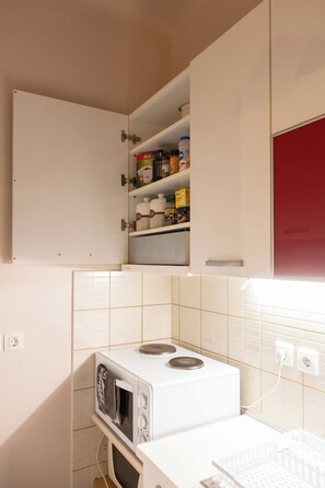 A compact kitchen with a microwave, stove, and a small cabinet with food items. - Penthouse-Acropolis view in Attiki Metro by MPS (Athina)