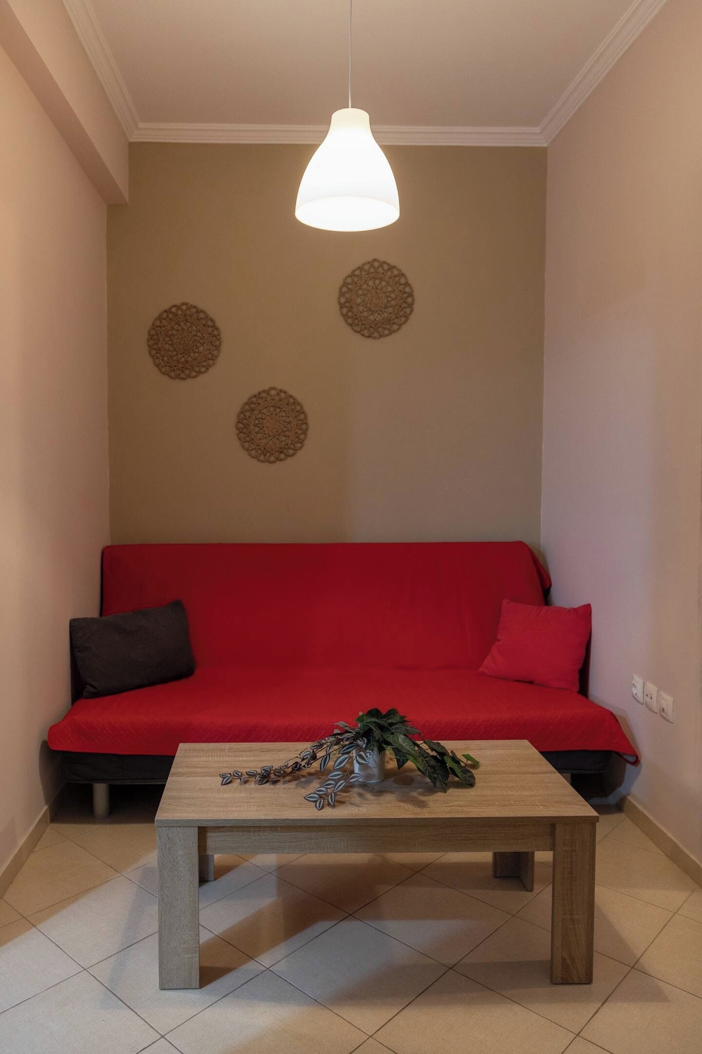 A room with a red sofa, a wooden coffee table, and decorative wall hangings.