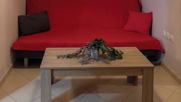 A room with a red sofa, a wooden coffee table, and decorative wall hangings.