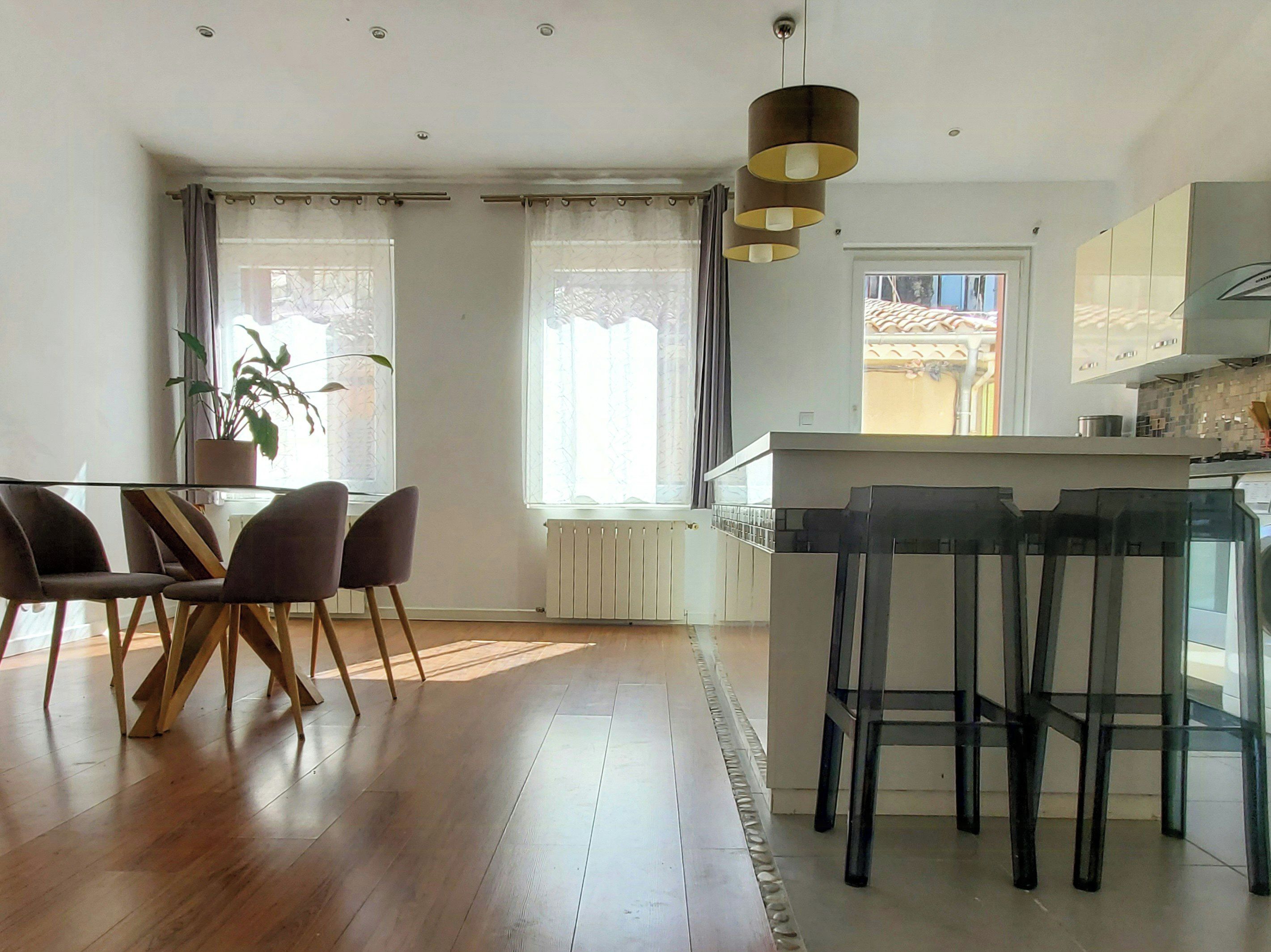 Eine moderne Küche mit einer zentralen Kochinsel, Barhocker und einem Essbereich mit Stühlen.