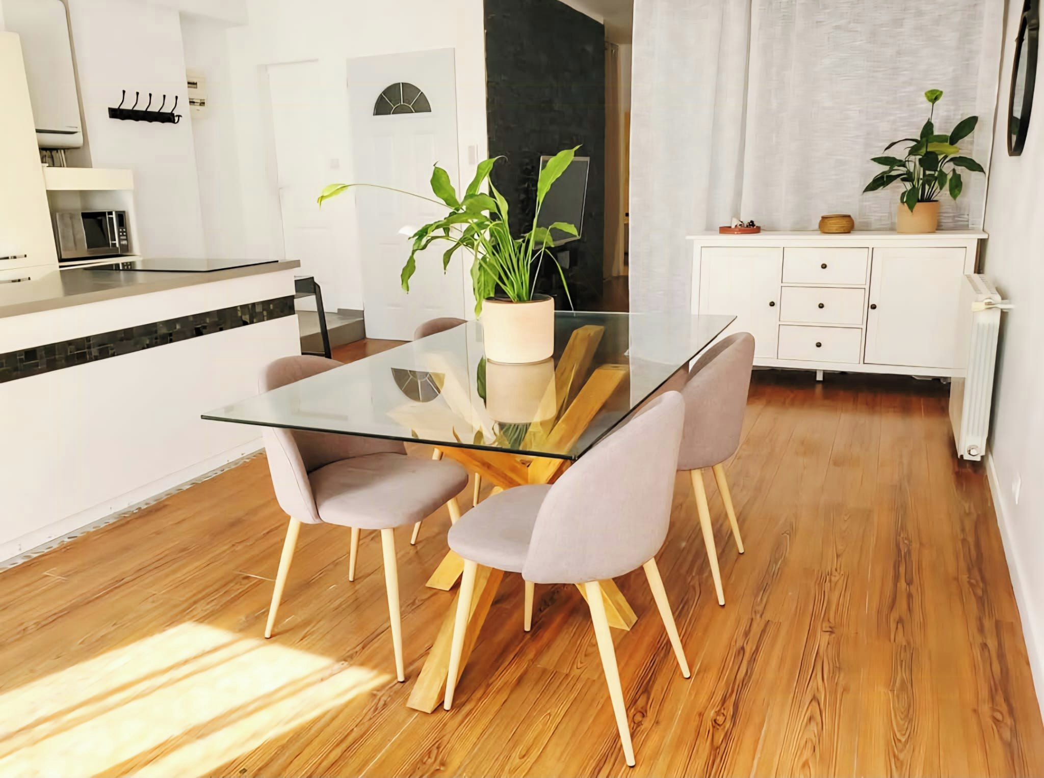 Een moderne keuken met een magnetron, een eettafel met stoelen en een potplant.