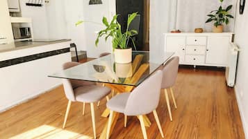 Een moderne keuken met een magnetron, een eettafel met stoelen en een potplant.