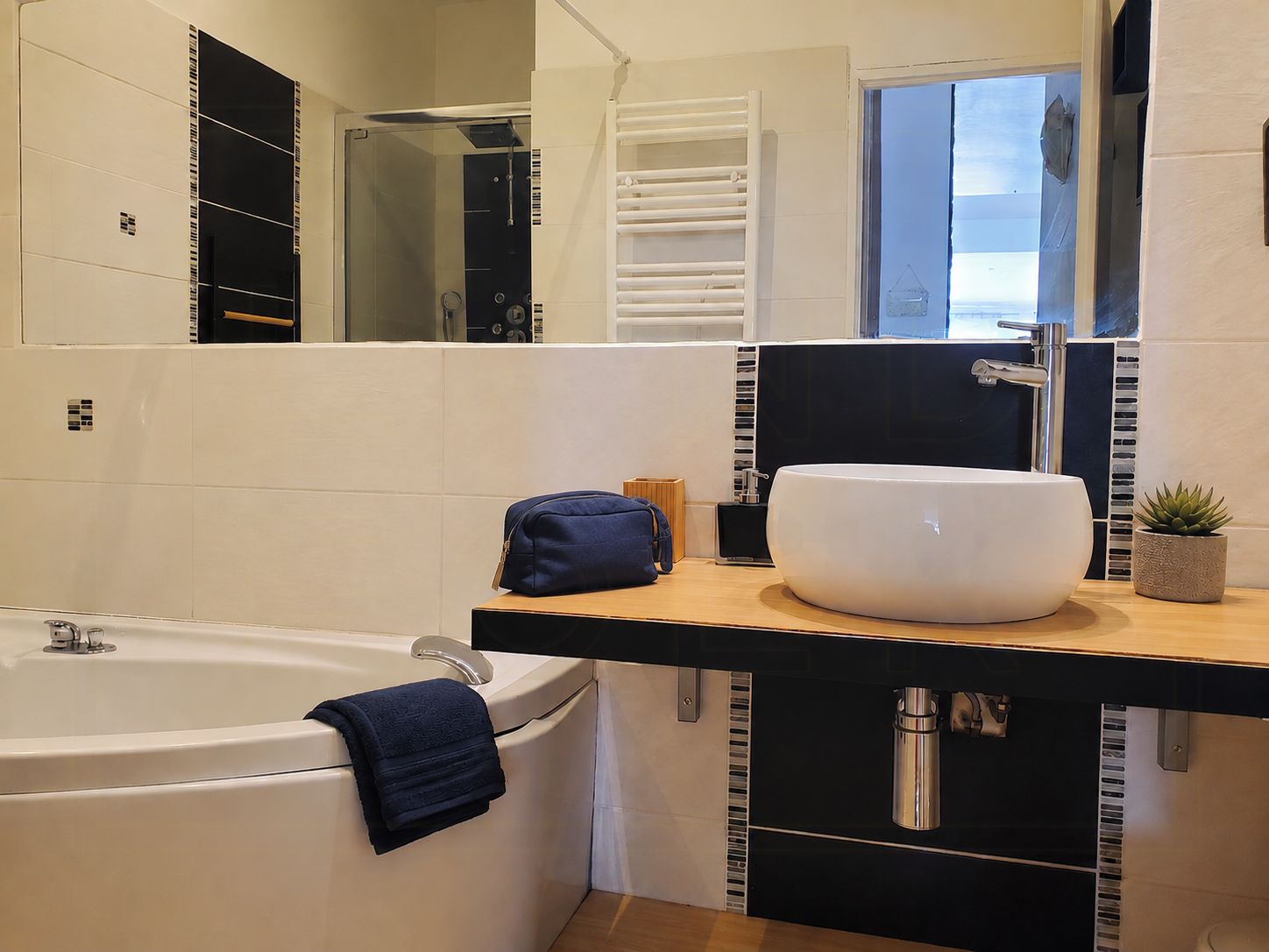 Une salle de bain moderne avec une grande baignoire, un lavabo blanc et un miroir au-dessus du lavabo.