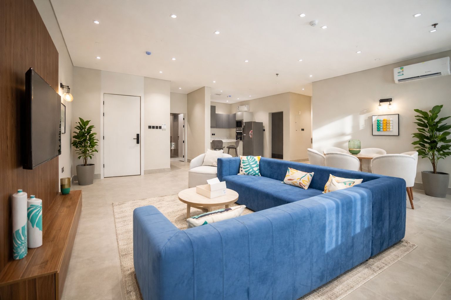 Un salon moderne avec un canapé bleu, une table basse et un téléviseur à écran plat fixé au mur.
