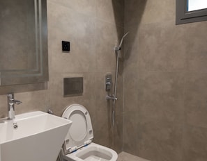 A modern bathroom with a white toilet, a sink, and a shower. - Wonderful 3-bedroom apartment with AC in vibrant riyadh (الرياض)