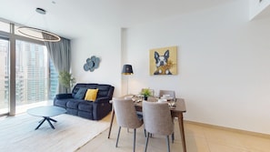 Een moderne woonkamer met een bank, eettafel, stoelen en kunstwerken aan de muur.