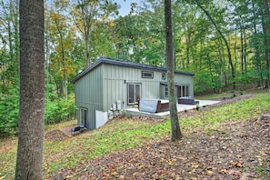 A small, single-story cabin with a covered patio area, surrounded by a forested landscape. - Escape to Pandapas Retreat! Enjoy a private hot tub, cozy comforts, and peaceful woodland scenery. (Newport)