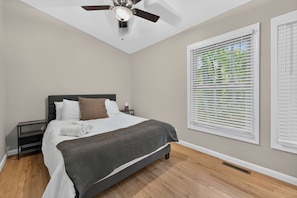 A bedroom with a bed, a nightstand, a ceiling fan, and a window with blinds. - Escape to Pandapas Retreat! Enjoy a private hot tub, cozy comforts, and peaceful woodland scenery. (Newport)