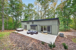 A modern house with a patio and outdoor seating area. - Escape to Pandapas Retreat! Enjoy a private hot tub, cozy comforts, and peaceful woodland scenery. (Newport)