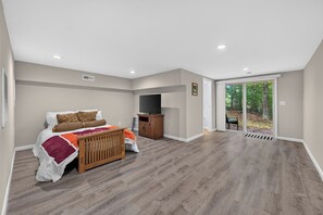 A bedroom with a bed, a television, and a view of the outdoors. - Escape to Pandapas Retreat! Enjoy a private hot tub, cozy comforts, and peaceful woodland scenery. (Newport)