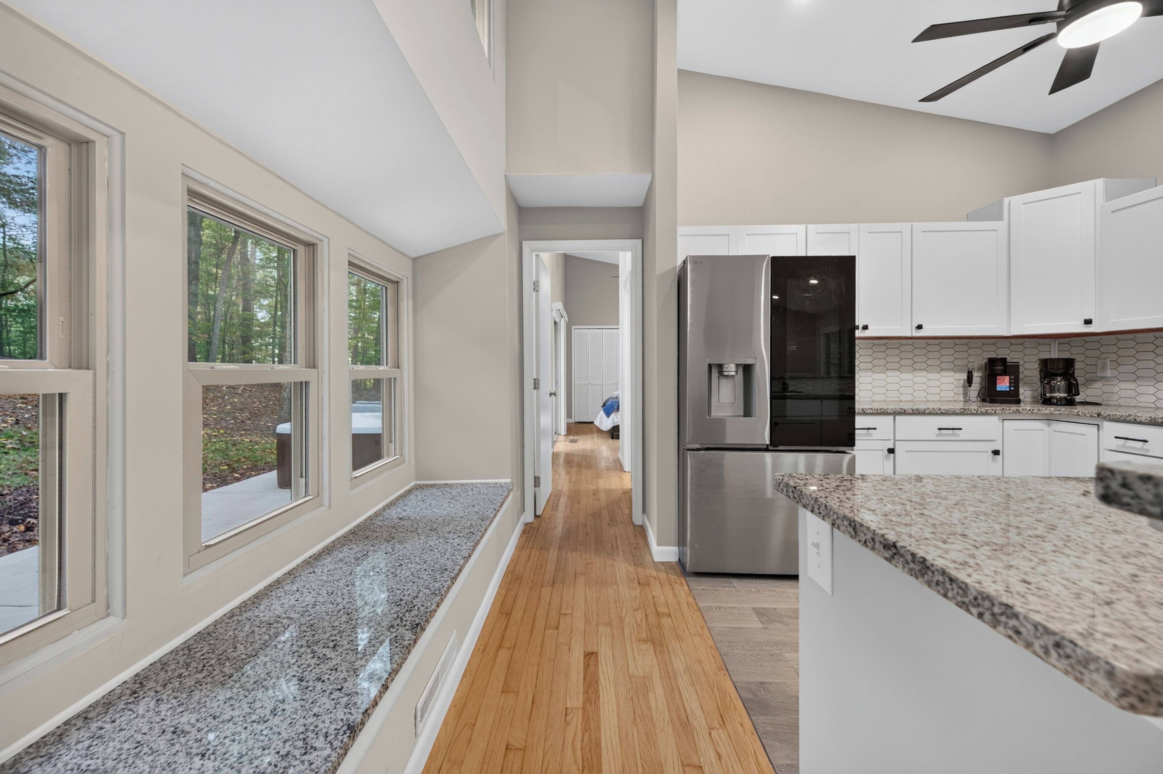 A modern kitchen with white cabinets, a stainless steel refrigerator, and a coffee maker.