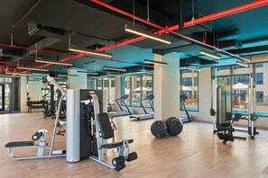 Una sala de gimnàstica amb equip d'exercici, grans finestres i un disseny modern.