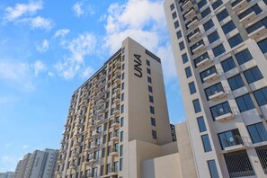 Een meerlaags gebouw met een opvallend ‘UNA’ bord op de gevel, wat aangeeft dat het een hotel is.
