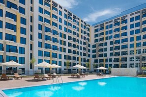 A hotel with a swimming pool, multiple floors, and outdoor seating areas. - Serene Studio in the Heart of Town Square l Cycling Track (Town Square)