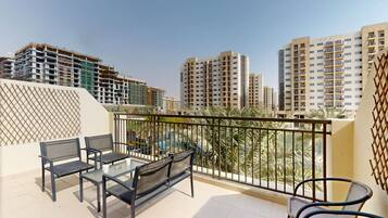 A balcony with a table and chairs, overlooking a cityscape with high-rise buildings.