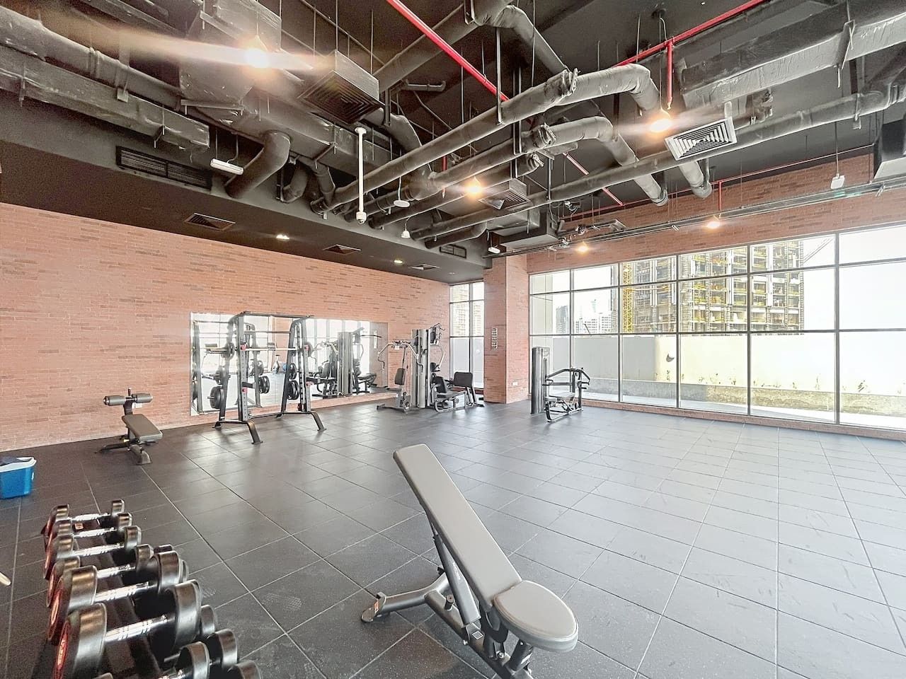 A gym with exercise equipment, a bench, and dumbbells.