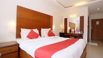 Una habitación de hotel con una cama grande, mesitas de noche, un espejo y una puerta.