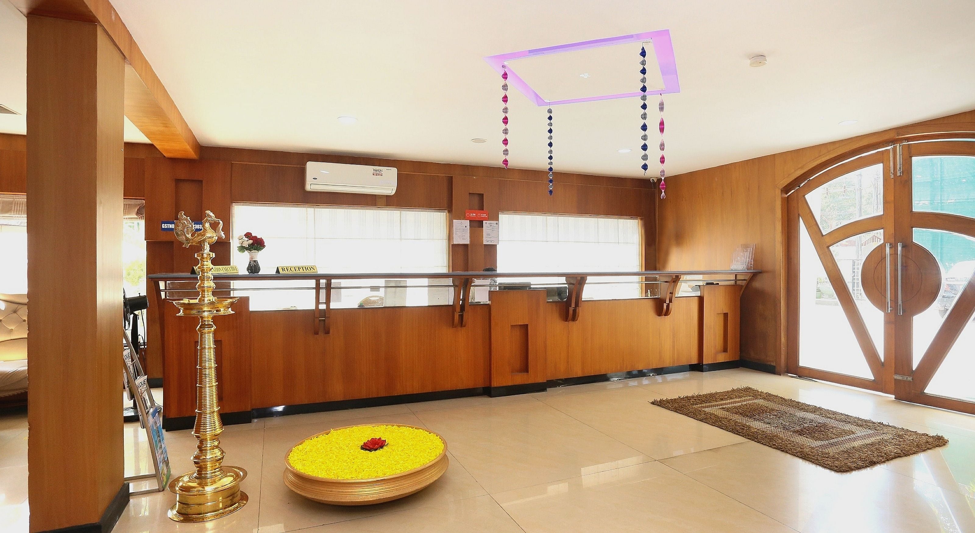 A reception area with a reception desk, a wall-mounted air conditioner, and a decorative brass lamp.