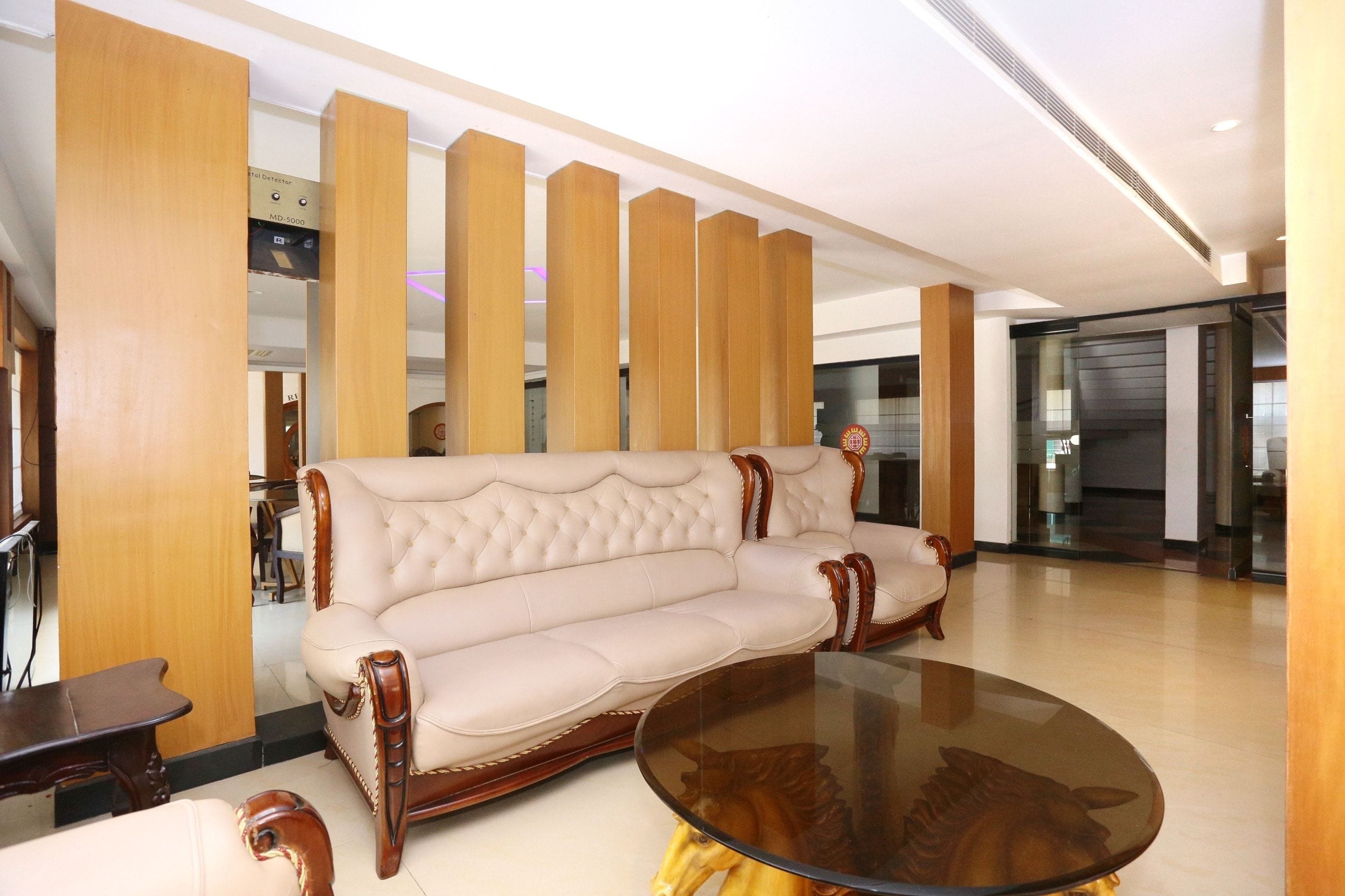 Een modern interieur met een beige gestoffeerde bank, een glazen salontafel en houten lambrisering.