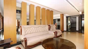 Een modern interieur met een beige gestoffeerde bank, een glazen salontafel en houten lambrisering.