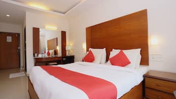 Een hotelkamer met een groot bed, een houten hoofdbord, een nachtkastje, een spiegel en een wandlamp.