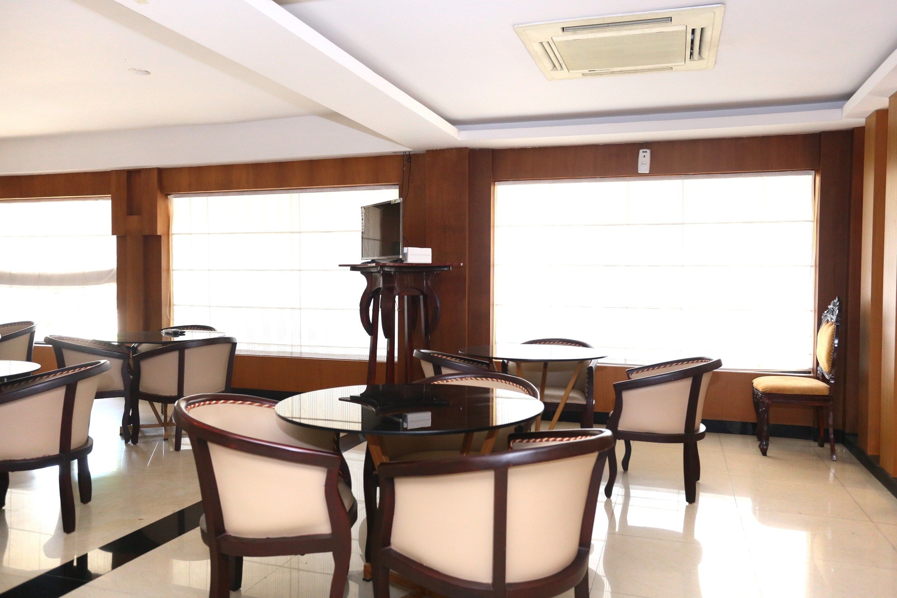 Una habitación de hotel con un ventanal grande, una mesa redonda y varias sillas.