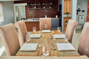 Un coin repas avec une table en bois dressée pour six personnes, entourée de chaises rembourrées.