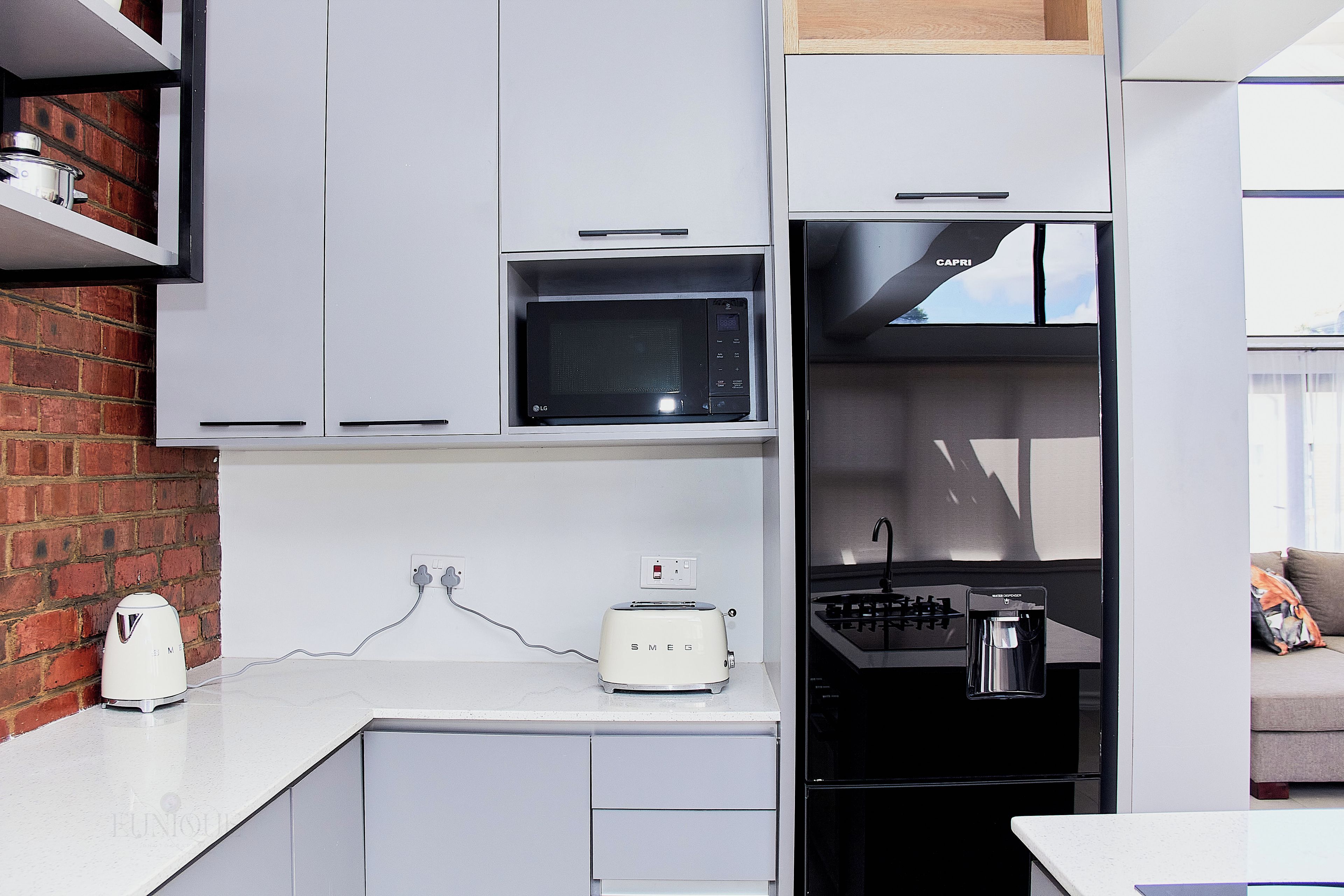 Eine kleine Küche mit Mikrowelle, Toaster und einem schwarzen Kühlschrank.