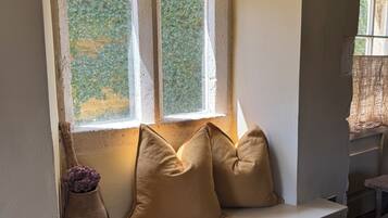 A room with a built-in bench under a window, a radiator below, and a small vase with flowers on the left.