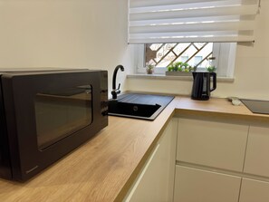 A kitchen with a built-in oven, a sink, and a window with blinds. - Vrbo Property (Roma)