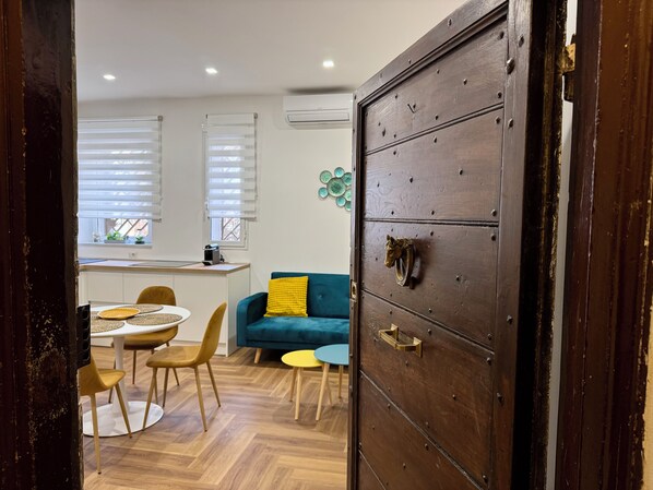 A room with a dining table, chairs, a sofa, and a large wooden cabinet with a brass handle. - Vrbo Property (Roma)