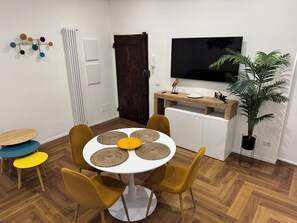 A dining area with a round table, four chairs, and a television above the counter. - Vrbo Property (Roma)