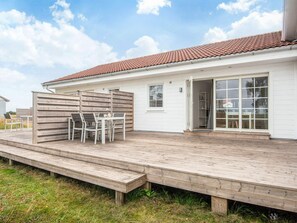 A house with a wooden deck, a patio table with chairs, and a sliding glass door. - 4 Person Holiday Home in Laeso (Læsø)