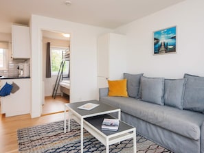 Ein modernes Wohnzimmer mit einem grauen Sofa, einem Couchtisch und einem Bild an der Wand.