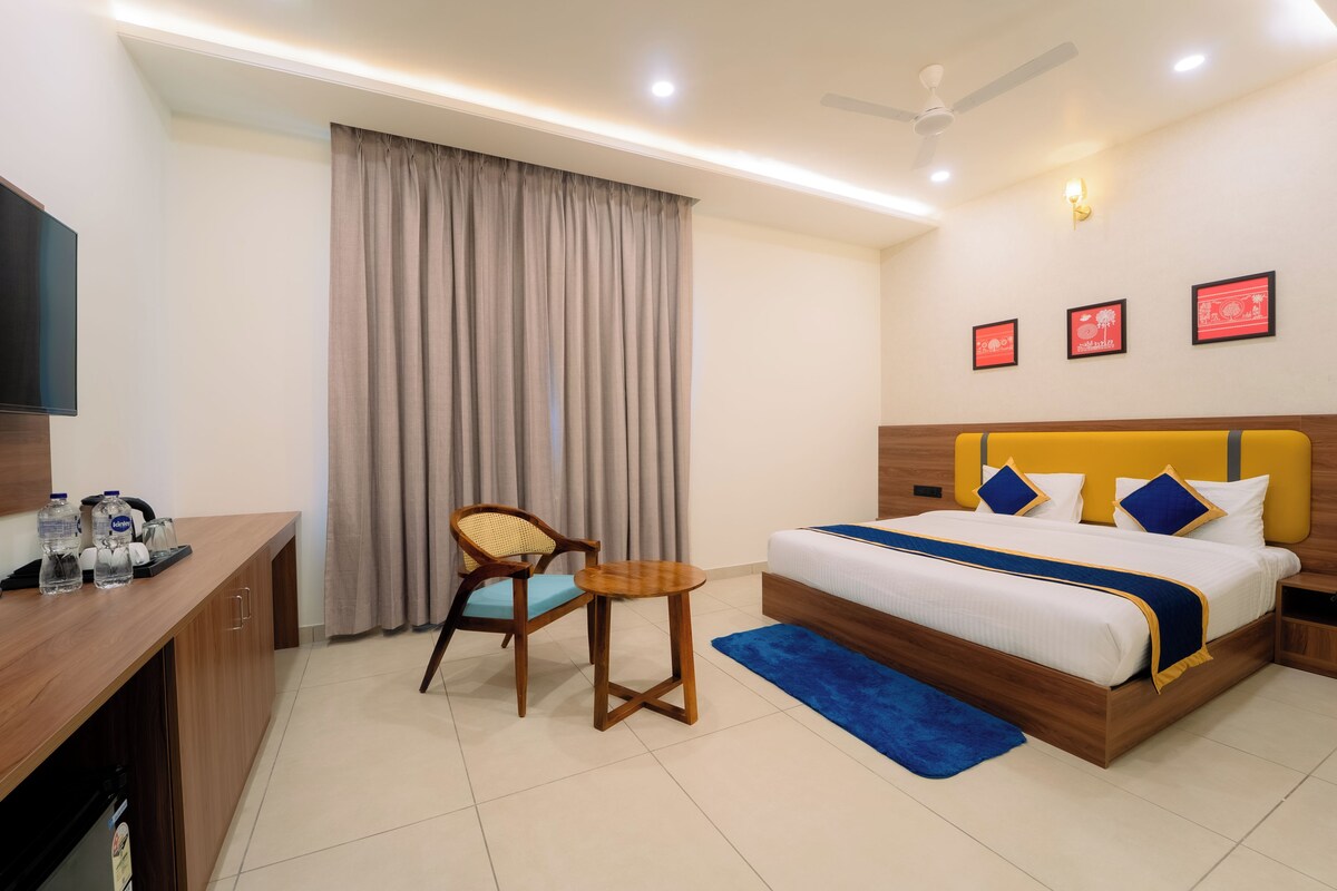 A hotel room with a bed, a desk, a chair, a TV, and a ceiling fan.