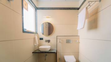 A compact bathroom with a sink, mirror, and toilet.