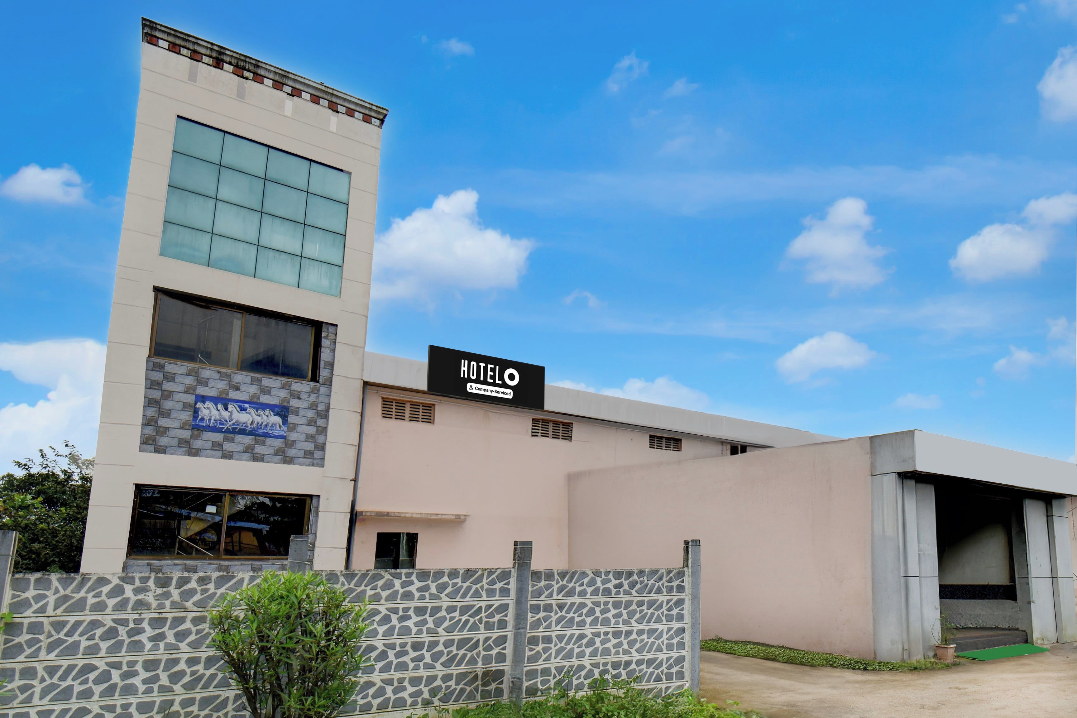 A modern hotel building with a sign indicating it is a company-serviced hotel.