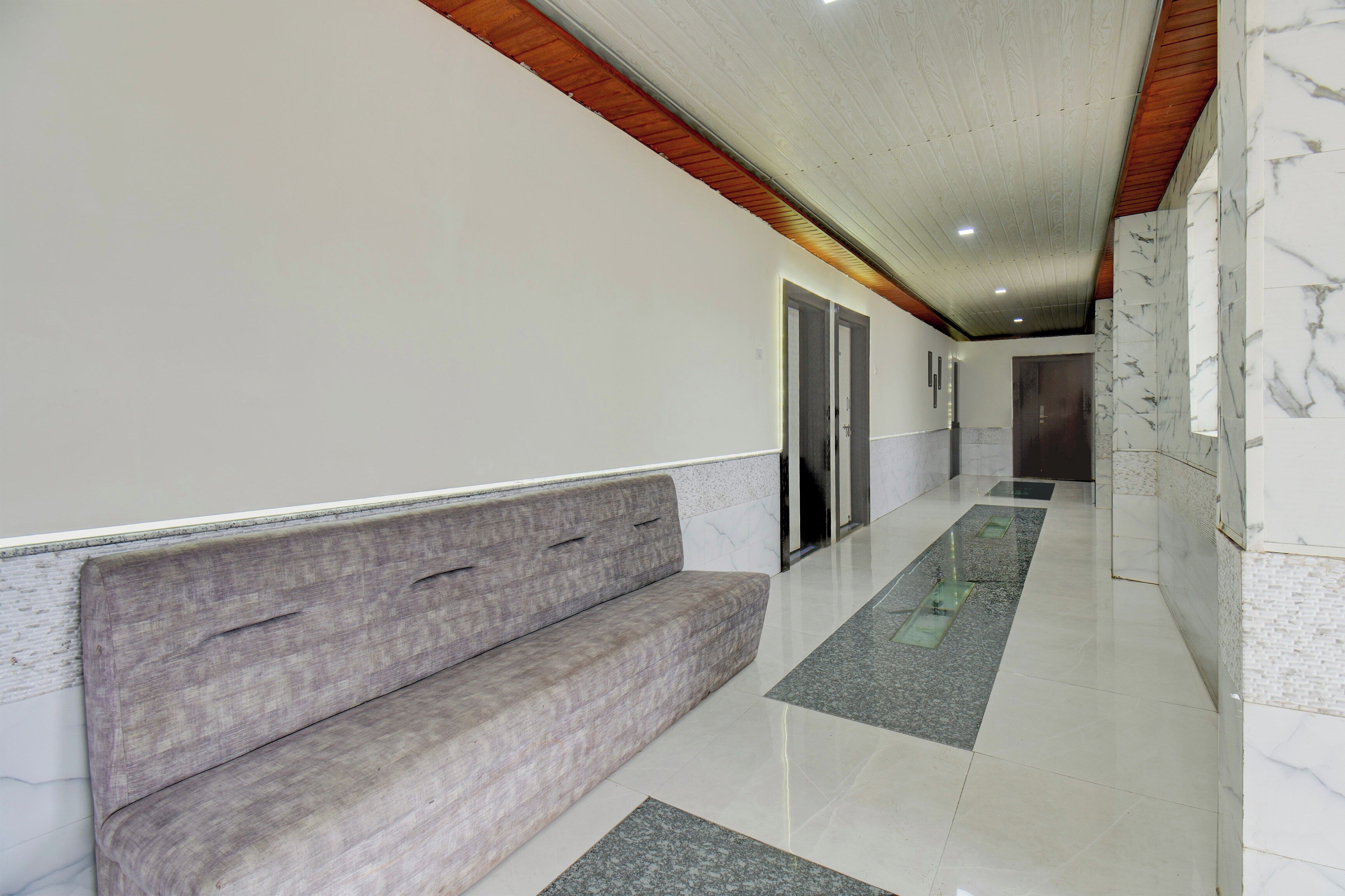 A hallway with a bench, a door, and a marble floor.