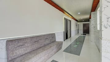 A hallway with a bench, a door, and a marble floor.