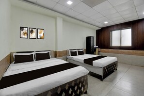 Habitación de hotel con dos camas, un ventanal grande y televisor montado en la pared.