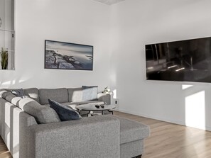 A modern living room with a grey sofa, a coffee table, and a large flat-screen TV mounted on the wall. - "Gerwendil" - 220m from the sea by Interhome (Sjølund)