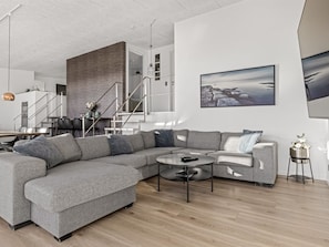 A modern living room with a grey sectional sofa, a round coffee table, and a large landscape painting on the wall. - "Gerwendil" - 220m from the sea by Interhome (Sjølund)
