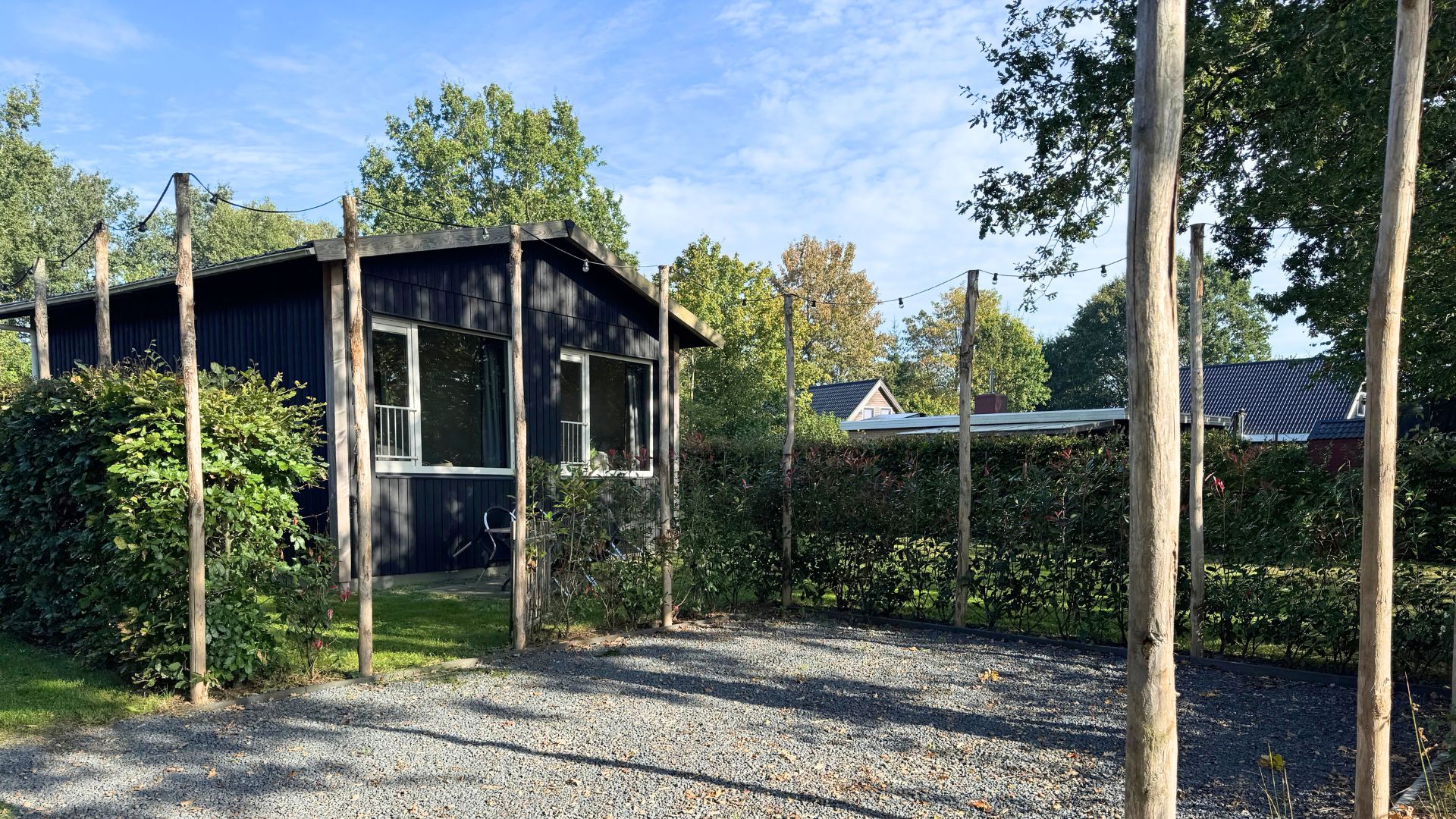 A house with a porch, surrounded by trees and a gravel driveway.