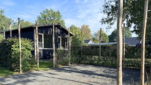 A house with a porch, surrounded by trees and a gravel driveway. - Get away from it all together in a completely detached tiny house on the edge of the Drenthe forest in Gasselte. (Gasselte)