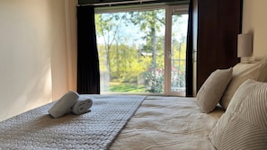 A hotel room with a bed, a window with curtains, and a view of greenery outside. - Get away from it all together in a completely detached tiny house on the edge of the Drenthe forest in Gasselte. (Gasselte)