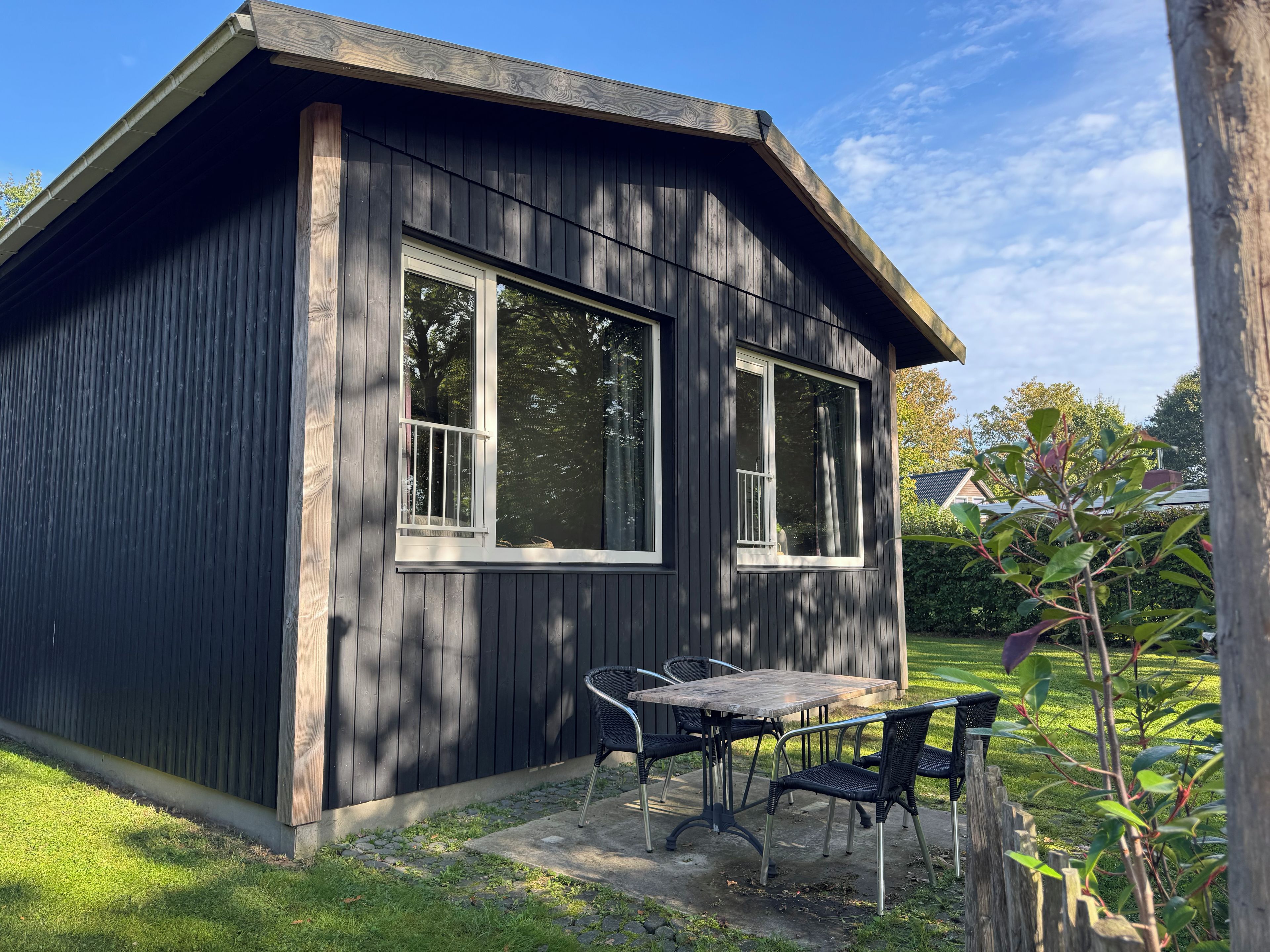A small wooden building with a balcony, a table, and two chairs.