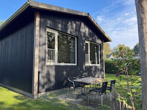 A small wooden building with a balcony, a table, and two chairs. - Get away from it all together in a completely detached tiny house on the edge of the Drenthe forest in Gasselte. (Gasselte)