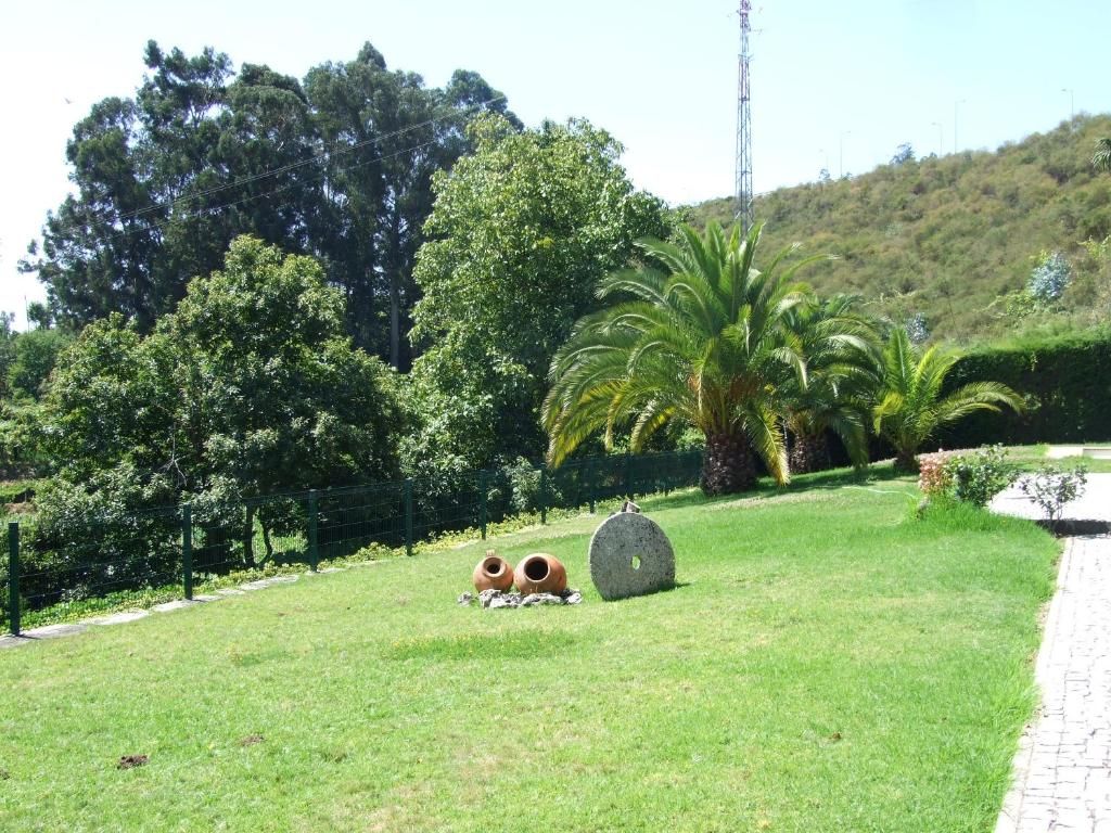 Un espacio con césped, un sendero, árboles y una alta torre de comunicaciones al fondo.